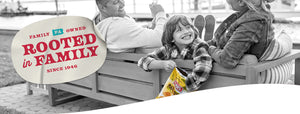 A couple sitting on a sofa with a child who is enjoying Herr’s BBQ Potato Chips. Family PA Owned Rooted in family since 1946.